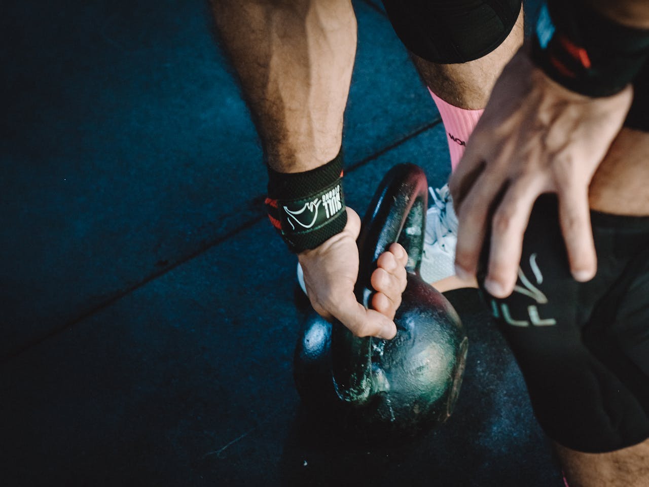 Muscular athlete lifting kettlebell during workout session, showcasing strength and fitness.