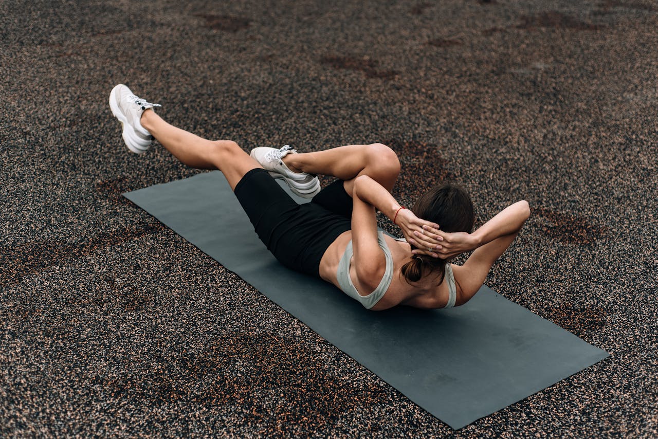 Fit woman doing a bicycle crunch on a mat outdoors, emphasizing core strength and fitness.